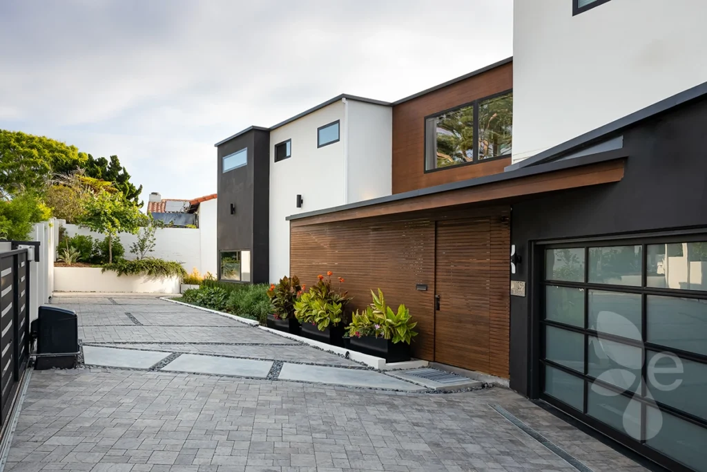 The driveway and front of the house, surrounded by landscaping and an enclosed fence.