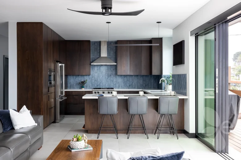 Kitchen with dark wood cabinets, fridge, stove, range hood, bar with accommodating seating.