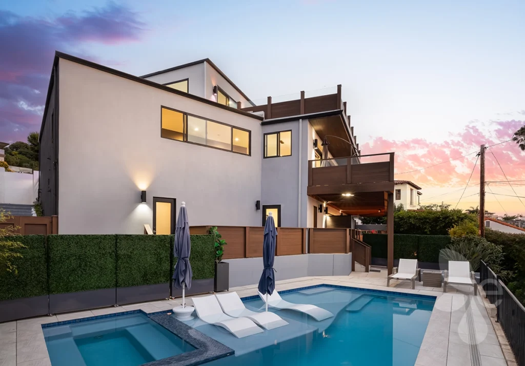 Backside of the house overlooking pool area with lounge chairs and multiple decks