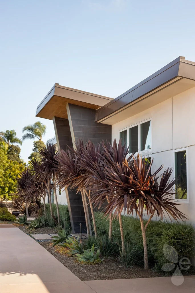 Front of home with landscaping, trees, and bushes in front.