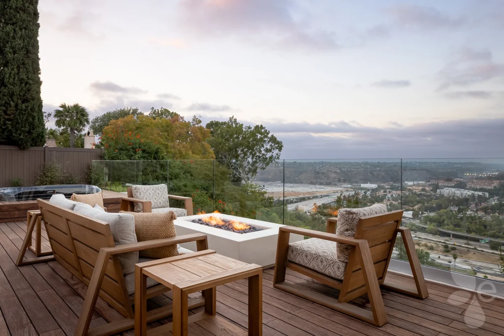 Outdoor lounge area with two chairs, couch, and fire pit. Overlooking San Diego.