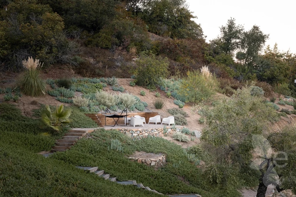 A zoomed out view of a seating area surrounded by hardscape and lush landscape