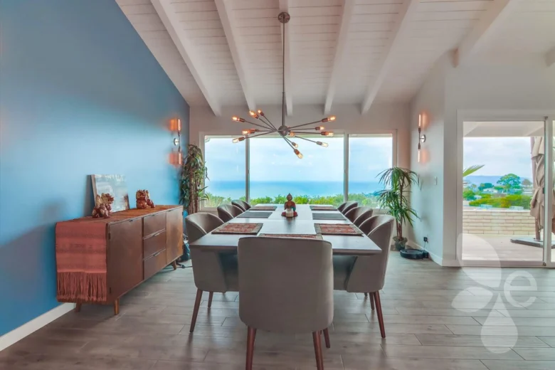 A straight on shot of a dining room, Dining room tables and chairs with light fixtures and windows