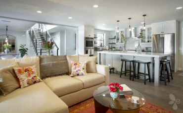 Home Interior Living Room with Couch, Round Table, View of the Kitchen to the Right and to the left is a staircase that leads upstairs